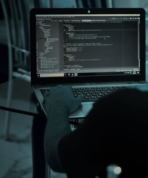 Homem sentado no escuro trabalhando no computador em um projeto de codificação