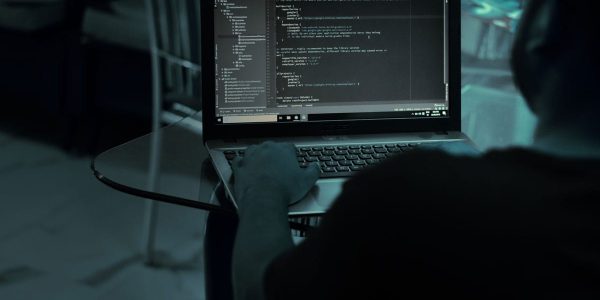 Homem sentado no escuro trabalhando no computador em um projeto de codificação