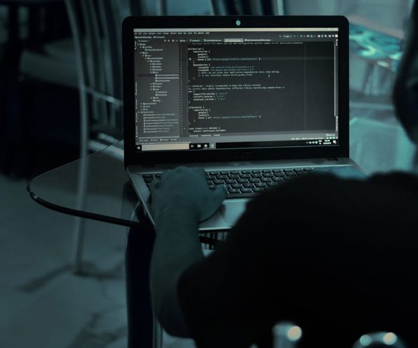 Homem sentado no escuro trabalhando no computador em um projeto de codificação